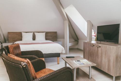 a bedroom with a bed and a tv and a chair at Terres de France - Appart'Hotel le Splendid in Allevard