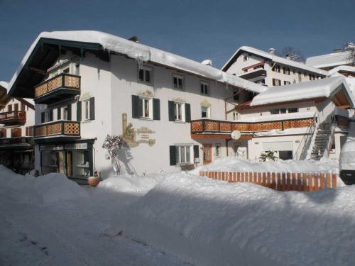 un edificio con un montón de nieve delante de él en Ferienwohnungen Rosenhof, en Tegernsee