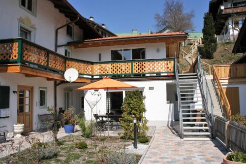 uma casa com um guarda-chuva e um pátio em Ferienwohnungen Rosenhof em Tegernsee