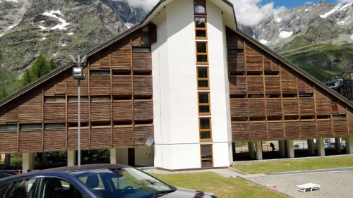un edificio en las montañas con un coche aparcado delante en Condominio Alpe Bardonay, en Breuil-Cervinia