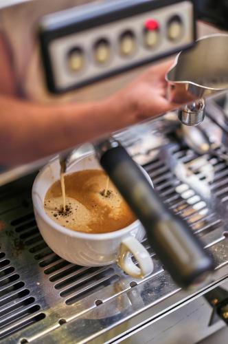 a person is making a cup of coffee at Hotel Eisensteiner Hof in Bayerisch Eisenstein