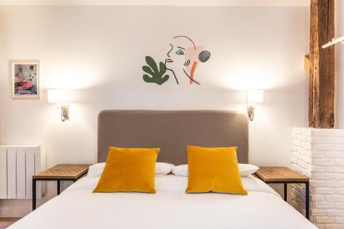 une chambre avec un lit blanc avec des oreillers jaunes dans l'établissement Design & New Loft in heart of Paris, à Paris