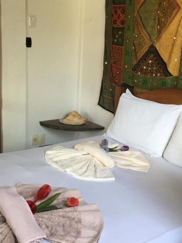 a bed with two towels and flowers on it at Casas Coloniais in Morro de São Paulo