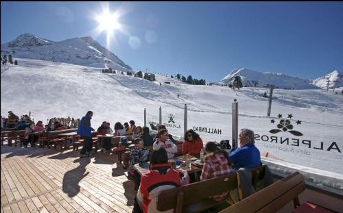 a group of people sitting on benches on a ski slope at Hotel Alpenrose aktiv & sport in Kühtai
