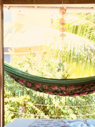 a hammock in front of a window with plants at Casas Coloniais in Morro de São Paulo