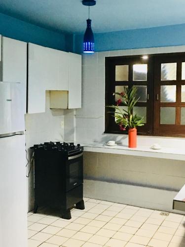 a kitchen with white cabinets and a black stove at Casas Coloniais in Morro de São Paulo