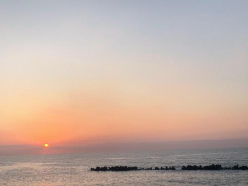 a sunset over the ocean with the sun in the sky at B&B MIKAWA 2 - Kanazawa Fish Harbour in Kanazawa