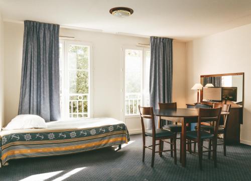 ラ・ロッシュ・ポゼにあるTerres de France - Appart'Hôtel La Roche-Posayのベッド、テーブル、椅子が備わるホテルルームです。