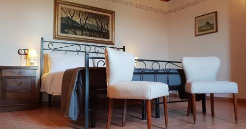 a bedroom with a bed with two white chairs at La Torre in Chianti in Siena