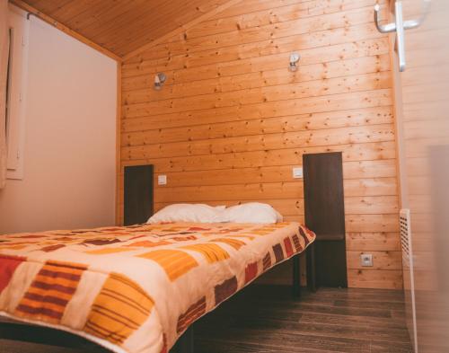 Cama en habitación con pared de madera en Terres de France - Les Hameaux des Lacs, en Monclar-de-Quercy