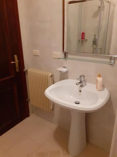 y baño con lavabo blanco y espejo. en Accogliente e confortevole appartamento a Tarvisio, en Tarvisio