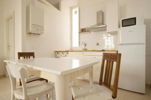 a white kitchen with a white table and chairs at Dimora Rugiada in Chieti