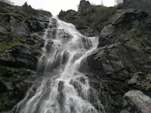 a waterfall on the side of a rocky mountain at Cabana Dara in Cumpăna