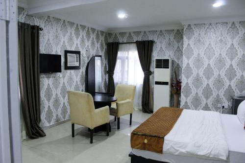 a bedroom with a bed and a desk and chairs at Galpin Suites in Ikeja