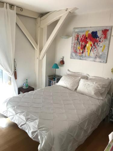 a white bed in a bedroom with a painting on the wall at Annie chambres hôtes in Cassagnabère-Tournas