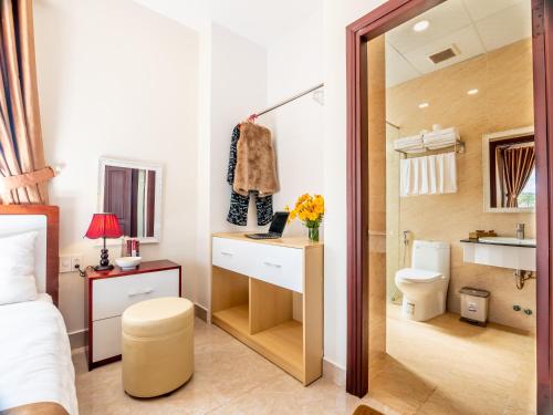 a bedroom with a bed and a desk and a bathroom at Aurora Hotel Dalat in Da Lat