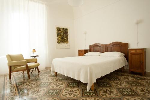 a white bedroom with a bed and a chair at Dimora Rugiada in Chieti
