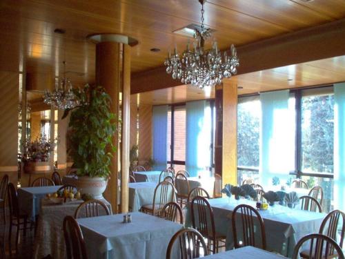 Loiano的住宿－皮內塔酒店，用餐室配有白色桌椅和吊灯。