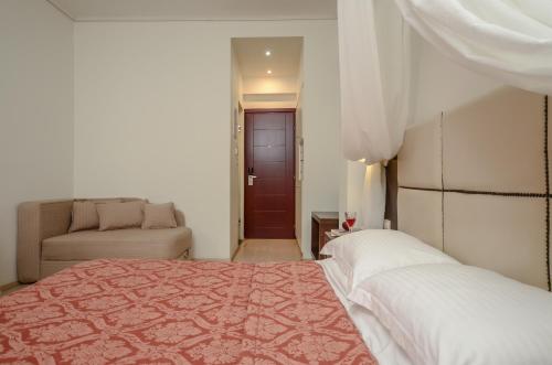 a bedroom with a bed and a couch and a chair at Aeolis Boutique Hotel in Naxos Chora