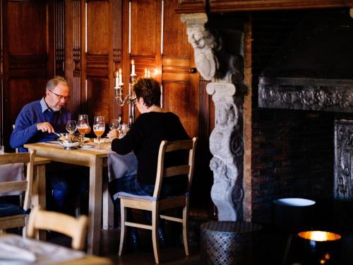 un homme et une femme assis à une table avec des verres à vin dans l'établissement Hotel L'O de Vie, à Saint-Trond