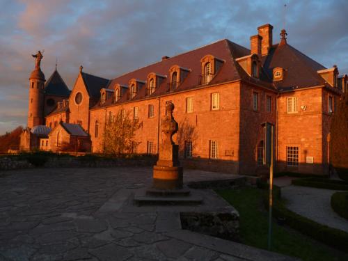 a large brick building with a statue in front of it at Hôtel-Restaurant Mont Sainte-Odile in Ottrott