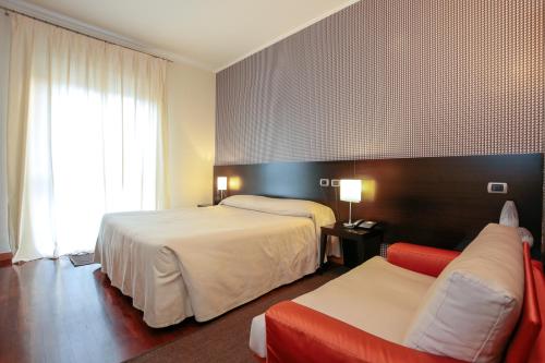 una camera d'albergo con due letti e un divano di Hotel Aleramo ad Asti