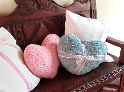 two heart pillows sitting on a wooden bench at Quinta Salinas - Puro Prazer in Aveiro