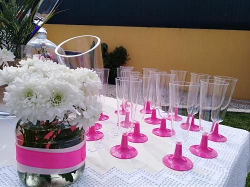 a table with pink glasses and a vase of flowers at Quinta Salinas - Puro Prazer in Aveiro