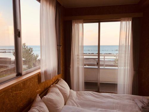 a bedroom with a bed with a view of the ocean at 富士山も見える静かな港町用宗のオーシャンビューゲストハウスRomey in Shizuoka