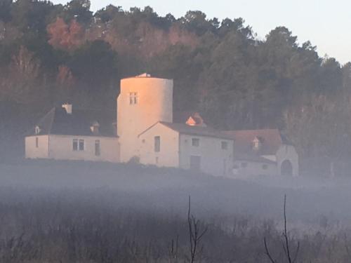 a white house in the middle of a foggy field at La Tour de Ginaillac in Les Arques