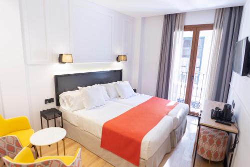 a hotel room with a bed with a orange blanket at Hotel Boutique Puerta de las Granadas in Granada