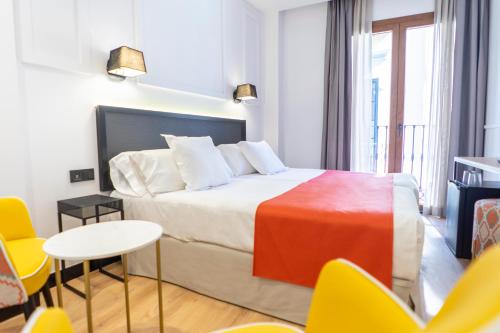 a bedroom with a bed and a table and chairs at Hotel Boutique Puerta de las Granadas in Granada