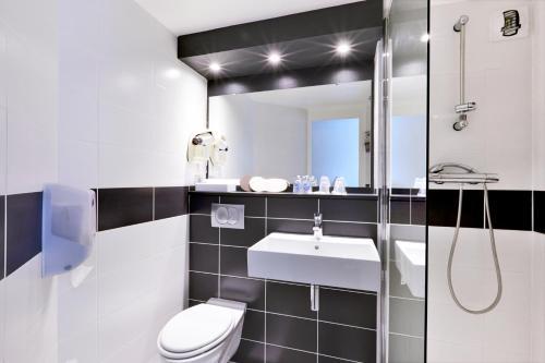 a bathroom with a toilet and a sink and a mirror at Kyriad Hotel Laval in Laval