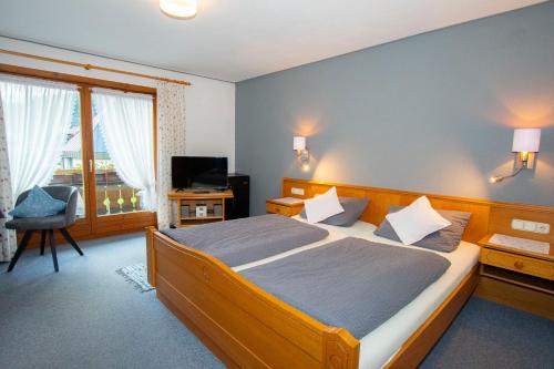 a bedroom with a large bed and a television at Gästehaus Christa in Obermaiselstein