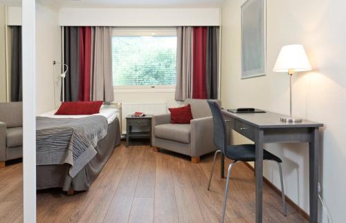 a hotel room with a bed and a desk and a chair at Hotelli Nuuksio in Espoo