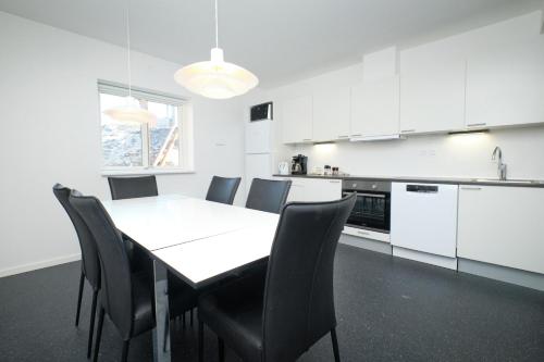 a kitchen with a white table and chairs in a room at Icefiord Apartments in Ilulissat