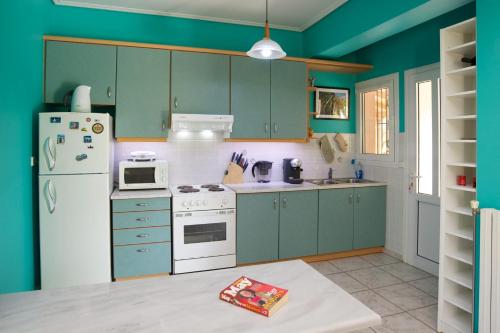 a kitchen with green cabinets and a white refrigerator at Emily Villas in Sami