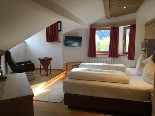 a bedroom with two beds and a chair and a window at Hotel Tyrolis in Zirl