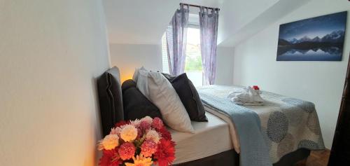 a bedroom with a bed with a table and flowers on it at Apartments Villa Bare in Kastav