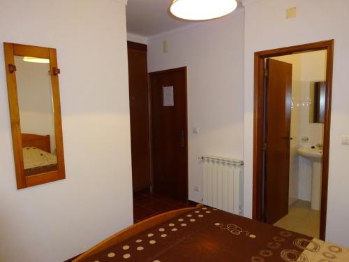a room with a bed and a mirror and a bathroom at Hospedaria Lampião in Penacova