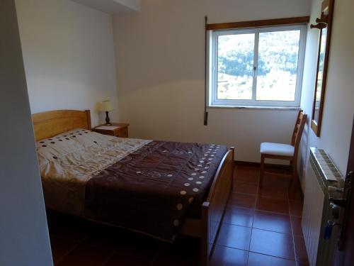 a bedroom with a bed and a window and a chair at Hospedaria Lampião in Penacova