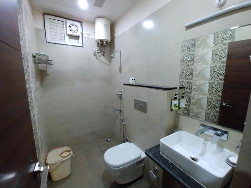 a bathroom with a white toilet and a sink at Blueberry Inn in Raipur