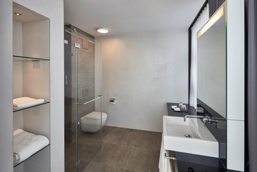 ein Bad mit einem Waschbecken, einem WC und einer Dusche in der Unterkunft Hotel Campus At Home in Planegg