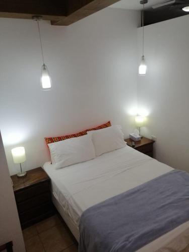 a bedroom with a white bed with two lights on it at Apartotel Don Francisco in San José