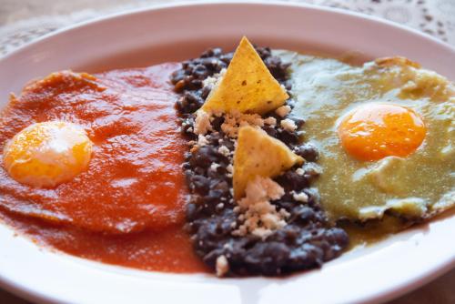 a white plate of food with beans and eggs at Hotel Camino Antiguo in Guanajuato