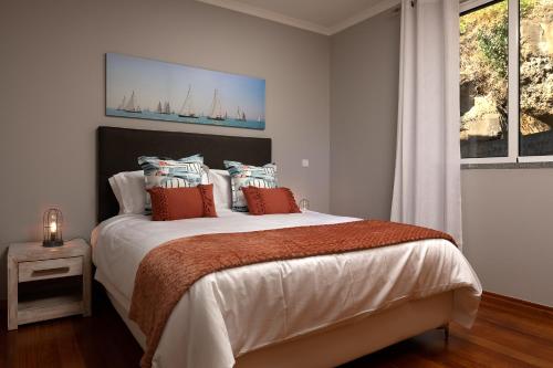 a white bedroom with a large bed with orange pillows at Peace Haven ll in Calheta