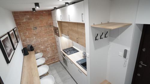 a small kitchen with white cabinets and a brick wall at Apartament Akali in Kielce