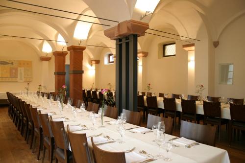 einen langen Tisch in einem großen Zimmer mit Tischen und Stühlen in der Unterkunft Rieslinghof in Wachenheim an der Weinstraße