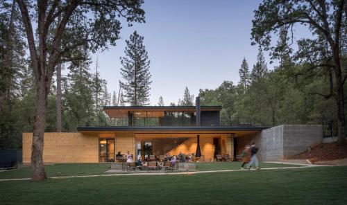 une maison dans une forêt avec des gens qui marchent devant elle dans l'établissement AutoCamp Yosemite, à Midpines