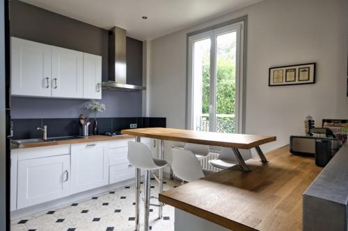 a kitchen with a wooden table and white cabinets at Villa Classée 4 étoiles Vue mer exceptionnelle in Trouville-sur-Mer